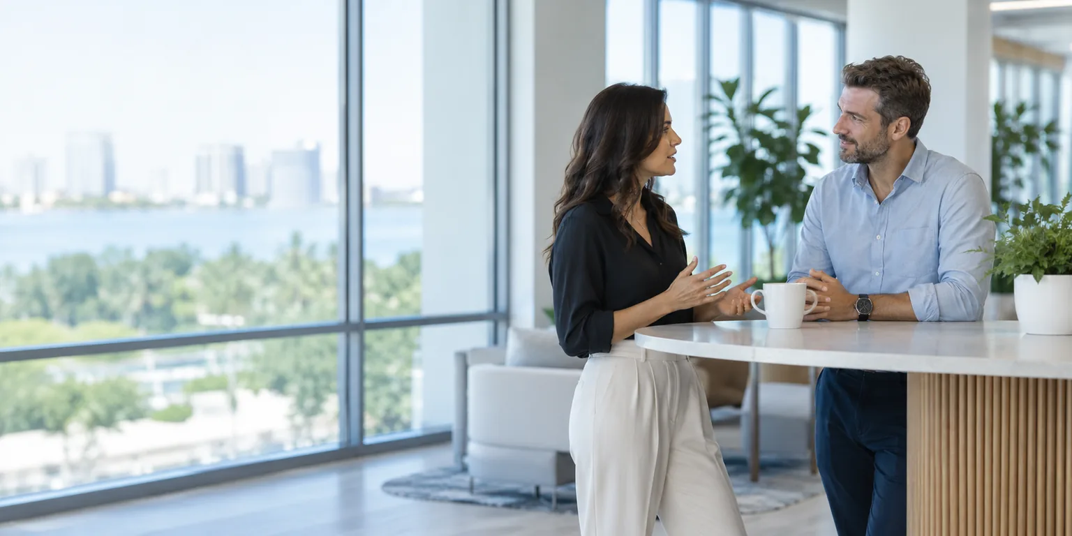Two professionals talking at a standing table in a bright office.